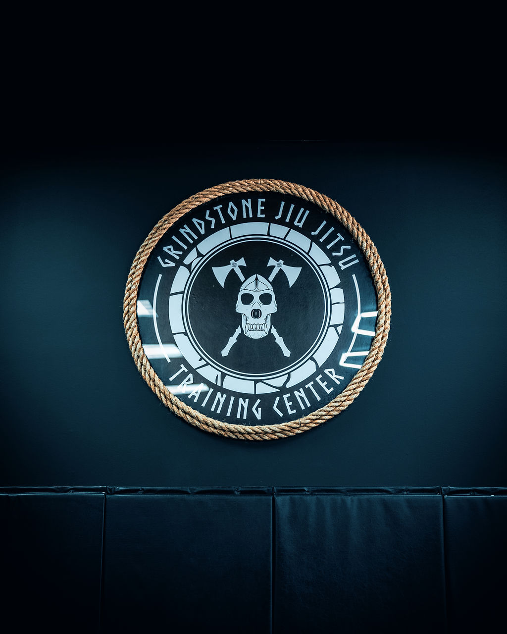 Grindstone Jiu Jitsu emblem mounted above the training mats