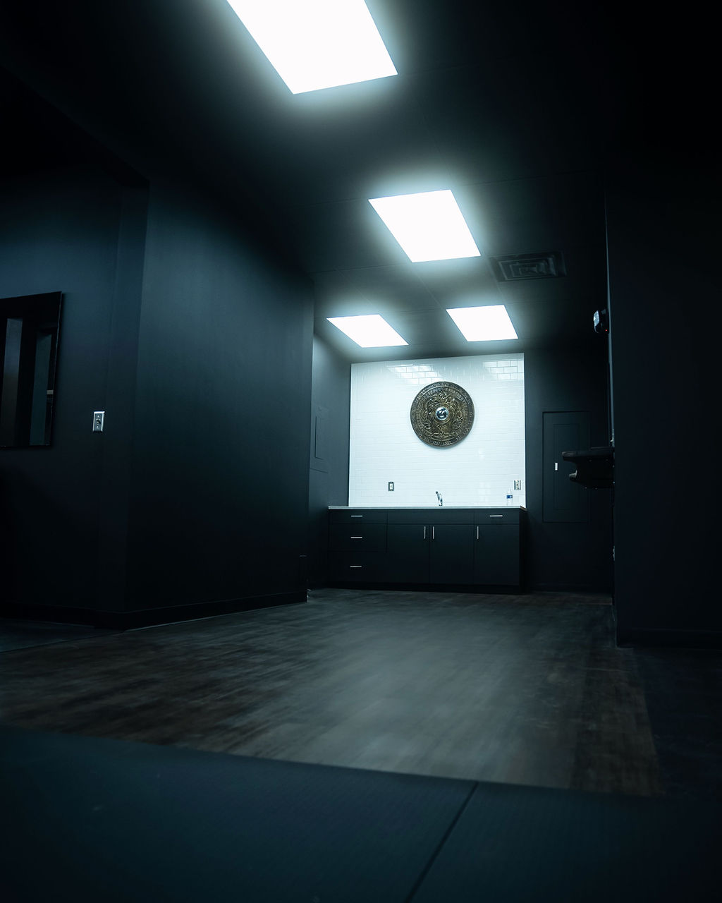 Dark facility corridor leading to a white tiled wall