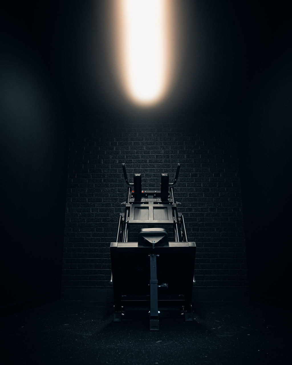 Strength machine beneath a single overhead light