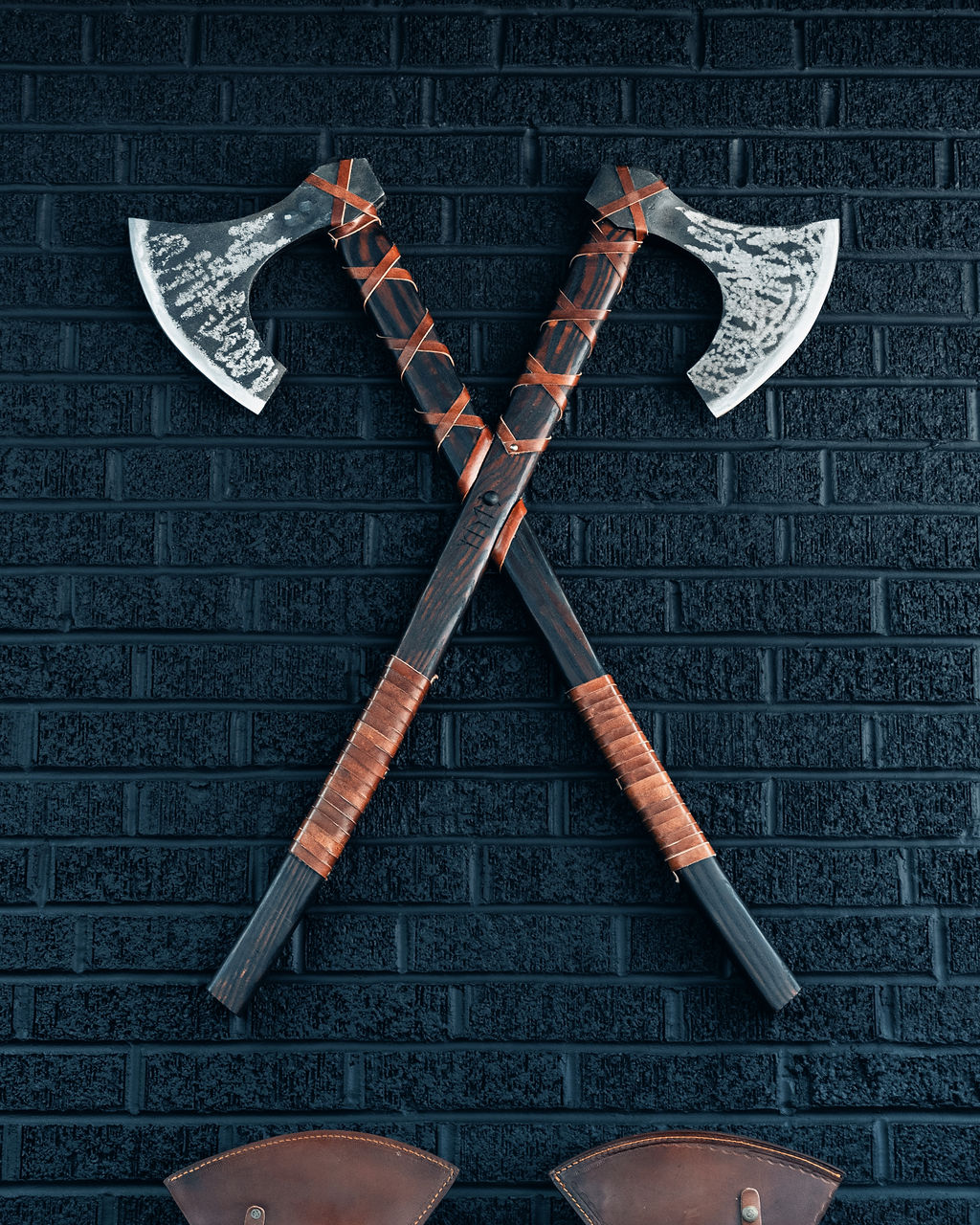 Crossed decorative axes on a black brick wall at Grindstone